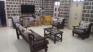 A living room with a sofa, armchairs, a coffee table, a TV, and a door with a window.