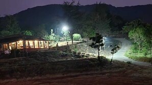 A building with a lit exterior, surrounded by trees and a hilly landscape.