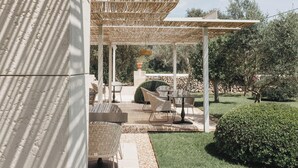 An outdoor patio with wicker furniture, a pergola, and a stone wall. - Agroturismo Malbuger Nou - Adults only (Mahón)