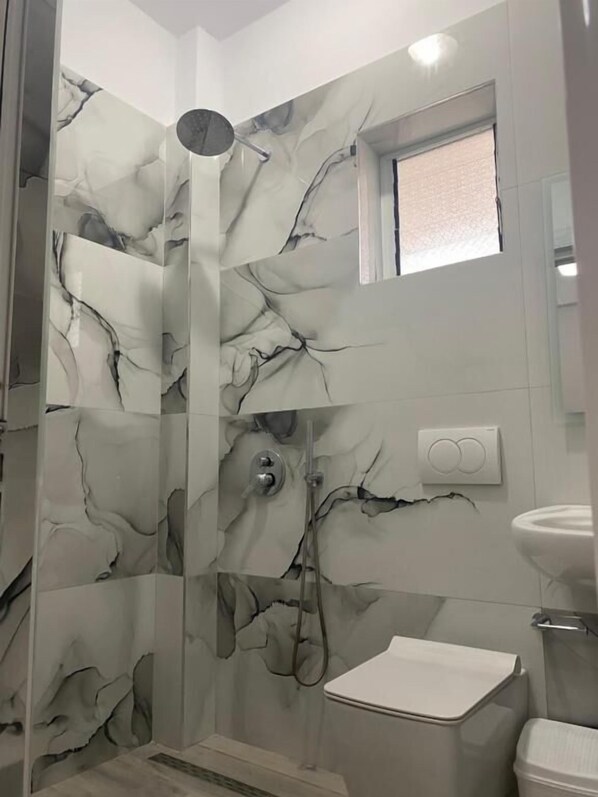 Um banheiro com box de vidro, pia branca e vaso sanitário.