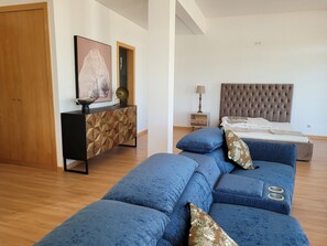 Quarto moderno com uma cama grande, um guarda-roupa de madeira, uma mesinha de cabeceira e um sofá azul.