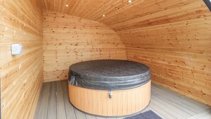 A wooden interior with a round hot tub in the center. - Laird Lodge 3 (Lochmaben)