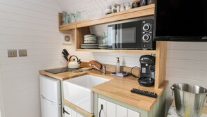 Une cuisine compacte équipée d’un four à micro-ondes, d’un évier et d’une machine à café.