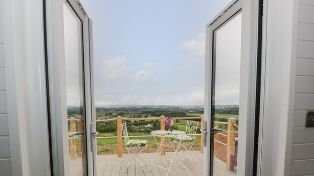Un balcon donnant sur un paysage rural, une table avec des chaises et un petit espace aménagé en jardin.