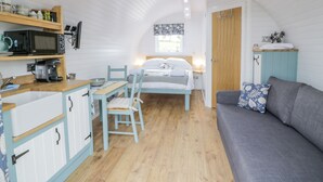 A cozy room with a bed, a sofa, a dining table, and a kitchenette. - Laird Lodge 2 (Lochmaben)