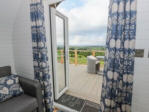 Ein Balkon mit Blick auf die Landschaft, ein Korbstuhl und eine Fußmatte mit der Aufschrift 'Welcome'.