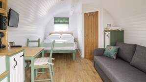 A cozy attic bedroom with a bed, a green chair, a gray sofa, a wooden desk, and a TV. - Laird Lodge 5 (Lochmaben)