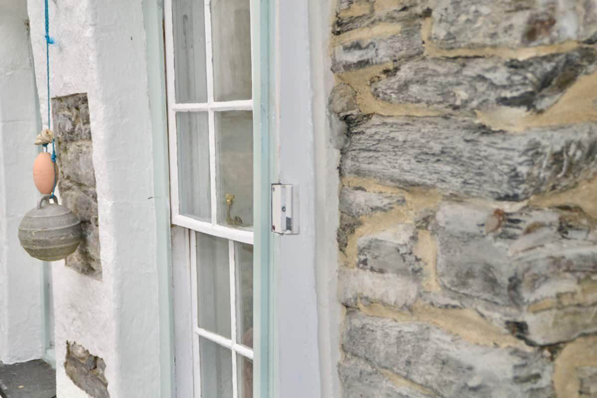 A stone wall adjacent to a white door with a window.