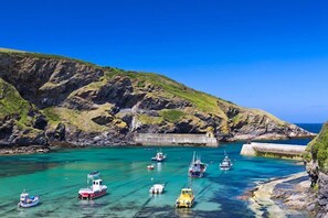 A coastal bay with boats anchored near a rocky breakwater. - Sunny Corner - A romantic and authentic fisherman's cottage, dating from 17th Century (Port Isaac)