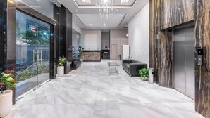 A modern lobby with a glass wall, a reception desk, and a chandelier. - GRAND   THAMRIN  HOTEL (Jakarta)