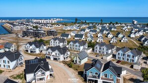 A coastal residential area with modern houses, a marina, and a clear view of the sea. - Sloop-Lounge - Fireplace, Infrared Sauna, Bathtub, Shower, Balcony, 2 Floors (Olpenitz)