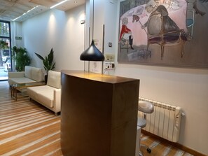 A reception area with a modern desk, a sofa, a radiator, and a painting on the wall.