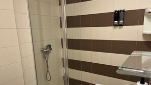 A modern bathroom with a glass shower enclosure, a white sink with a cup holder, and a towel rack with two black soap dispensers. - León Apartments. 20 years of success. Centrally located and recently air-conditioned (León)