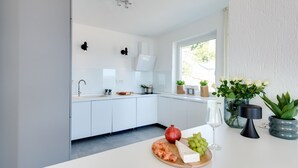 Una cocina moderna con armarios blancos, horno empotrado y ventana que deja entrar luz natural.