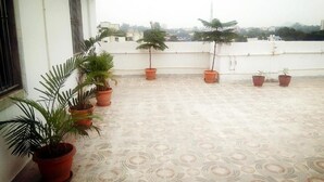 Una terraza en la azotea con plantas en macetas y suelo estampado.