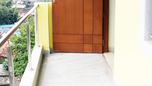 Un balcón con puerta de madera y barandilla de metal.