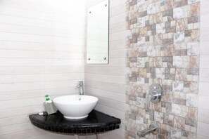 Un baño con un lavamanos blanco, un espejo y una pared con azulejos.