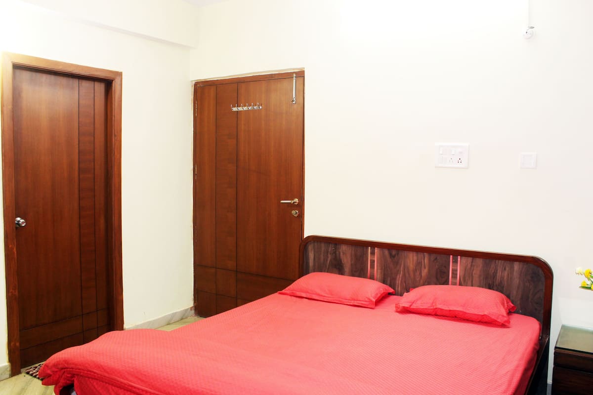 Un dormitorio con cama de madera, un armario de madera y una pared blanca con toma de corriente.