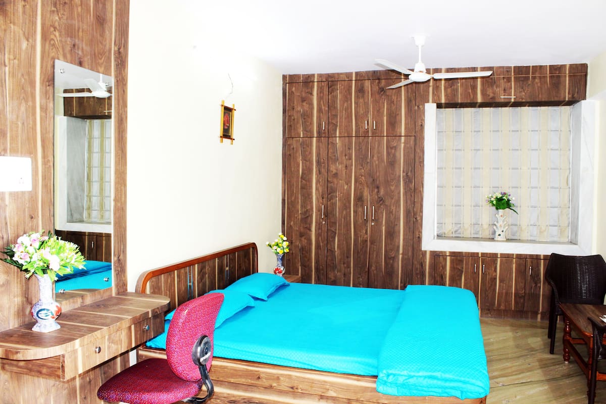 Un dormitorio con cama, muebles de madera, ventana con vistas y ventilador de techo.