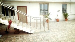 Amplio espacio interior con una escalera que conduce a un nivel superior. Se ven plantas en macetas y una puerta.