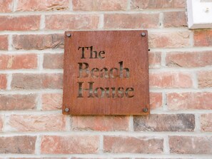 Une pancarte sur un mur de briques où l’on peut lire : « The Beach House ».