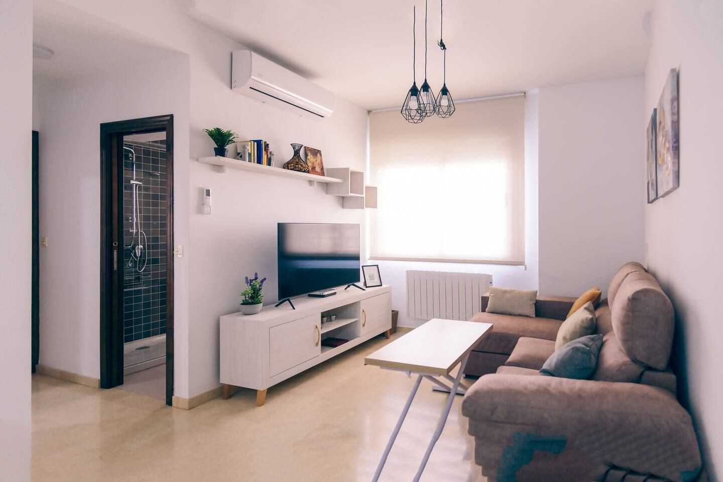 A modern living room with a flat-screen TV, a sofa, a coffee table, and a radiator.