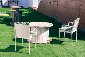 Un espace extérieur aménagé avec une table ronde et deux chaises, entouré de gazon synthétique.
