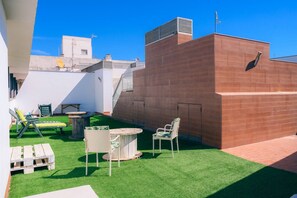 Une terrasse sur le toit avec une pelouse verdoyante, une table ronde et deux chaises.