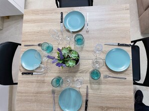 A dining table set with blue plates, cutlery, and glasses, surrounded by chairs. - Yaye House, Écija (Ecija)