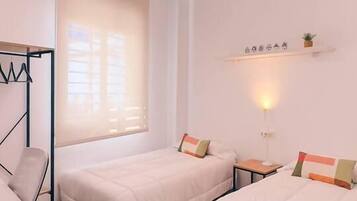 A bedroom with two beds, a desk, a chair, and a ceiling light fixture.