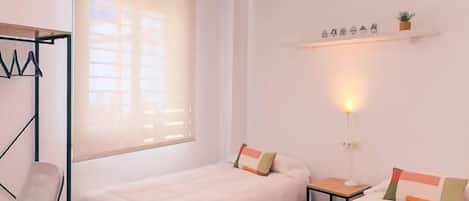 Un dormitorio con dos camas, un escritorio, una silla y una lámpara en el techo.