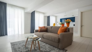 A modern living room with a sofa, a glass coffee table, and a kitchen in the background. - App 6 - Centrale Mazzoni (Venecia)