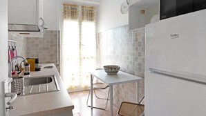 Eine Küche mit Spüle, einem weißen Kühlschrank, einem Tisch mit Schüssel und einem Stuhl.