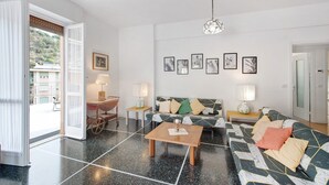 Ein modernes Wohnzimmer mit einer Couch, einem Couchtisch und Lampen. Eine Tür führt nach draußen, und an der Wand hängt ein Kunstwerk.