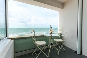 A balcony with a view of the sea, two white chairs, and a small table with a candle. - Tides - Beach Front Apartment in Bracklesham Bay (Chichester)