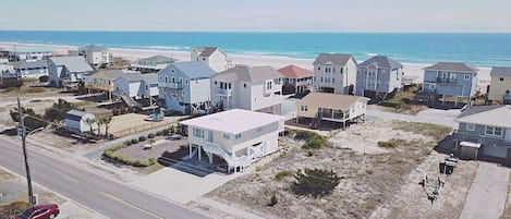 A coastal residential area with houses, a beach, and a road.