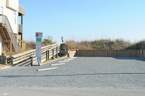 Schild für den Zugang zum Strand, ein Holzsteg und ein Gebäude mit einer Rampe.