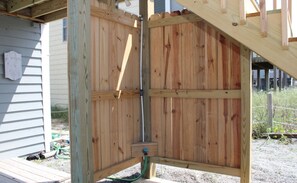 A wooden fence structure with a corner post and a hose attached to it.