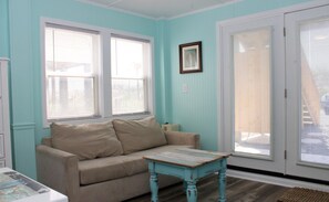 A room with teal walls, a beige sofa, a small table, and a door with a window.