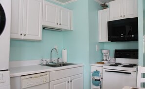 A kitchen with white cabinets, a black microwave, a coffee maker, and a stove.