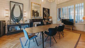 Una habitación amplia con una gran mesa de comedor, varias sillas, un televisor y objetos decorativos.
