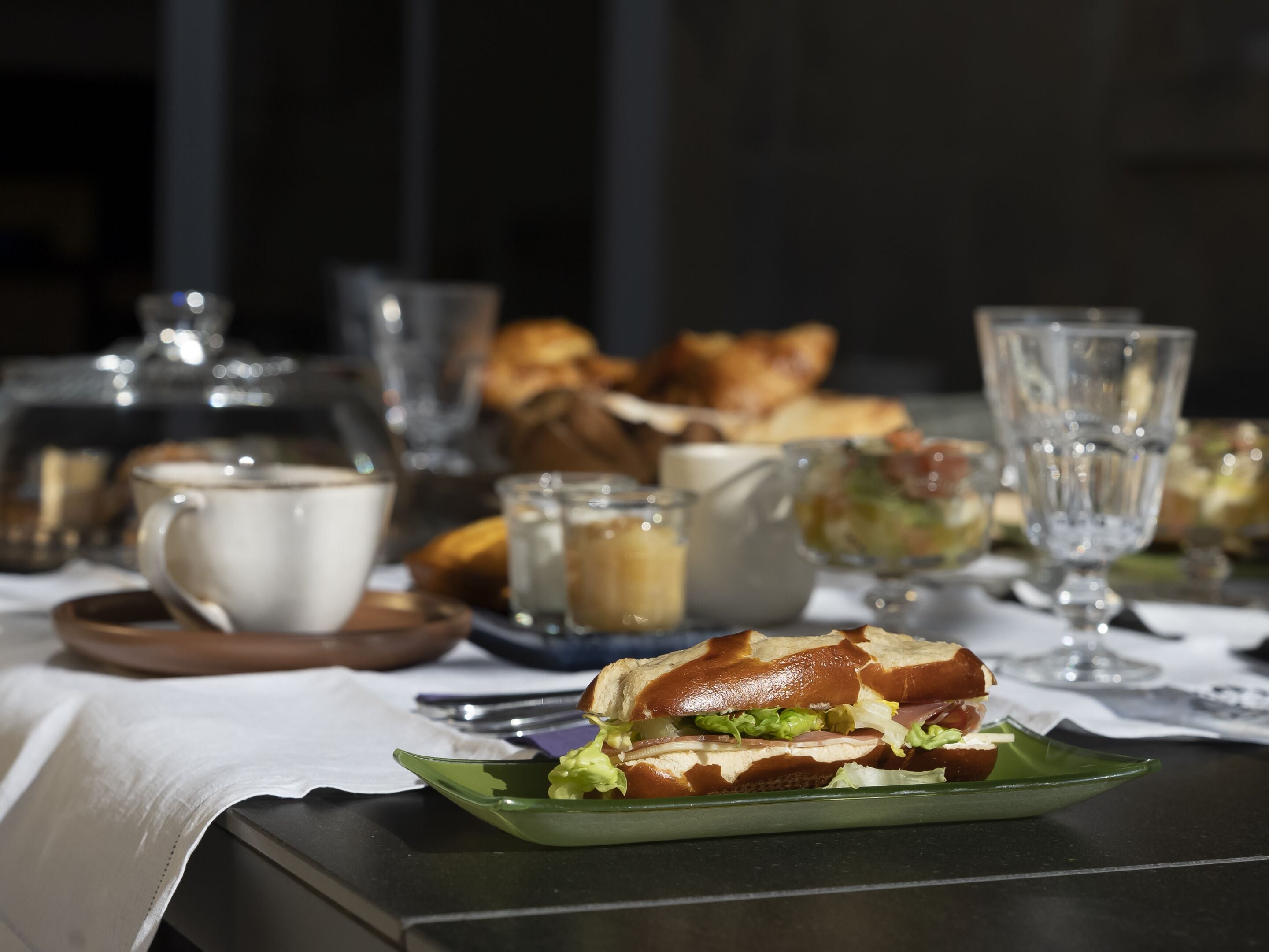 A table with a sandwich, a cup, and a pitcher.