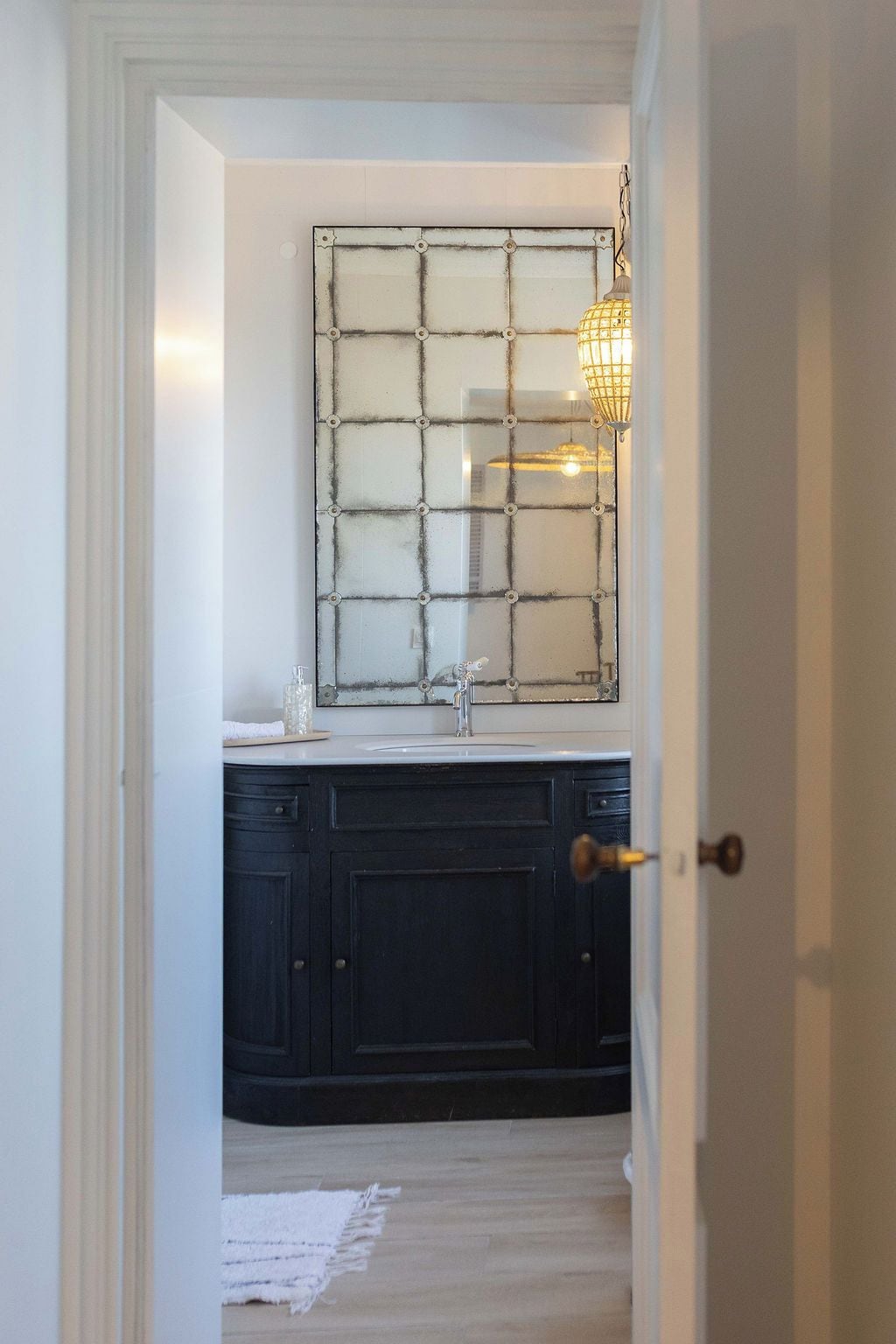 A bathroom with a dark wooden vanity, a white sink, and a mirror with a grid pattern.