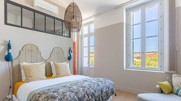 Une chambre à coucher avec un lit, une chaise, une fenêtre et un luminaire suspendu.