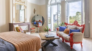 A well-lit bedroom with a large bed, a sofa, a coffee table, and a fireplace.