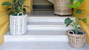 A grand staircase with a wrought iron railing, leading to a landing with a large mirror and wicker baskets with plants. - La Maison Mulato Bordeaux, Saint-emilion (Libourne)