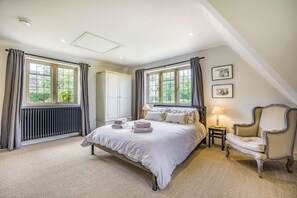Ein Schlafzimmer mit einem großen Bett, zwei Nachttischlampen, einem Sessel und einer Heizung.