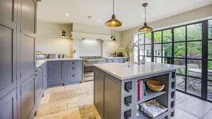 A modern kitchen with grey cabinets, a central island, and pendant lighting. - Large family friendly holiday home in the Cotswolds - Willows House (Lower Swell)