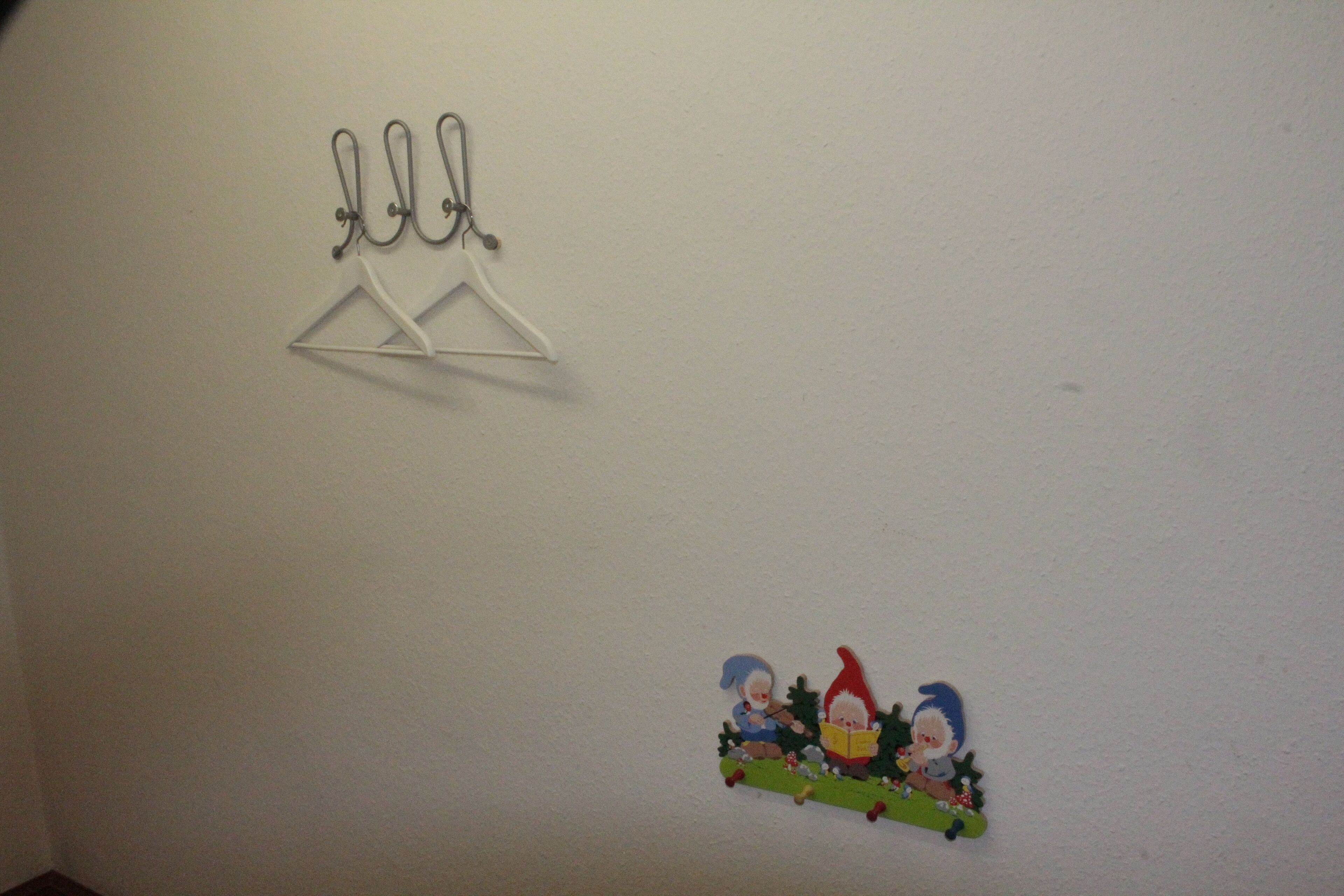 A wall with a coat rack and a decorative scene of two gnomes.