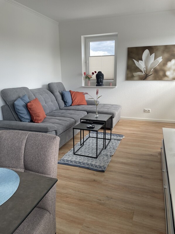 A modern living room with a grey sectional sofa, a small black coffee table, and a blue patterned rug.